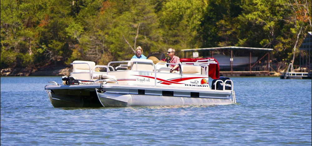 Older couple driving a boat covered by recreational insurance on a sunny day.